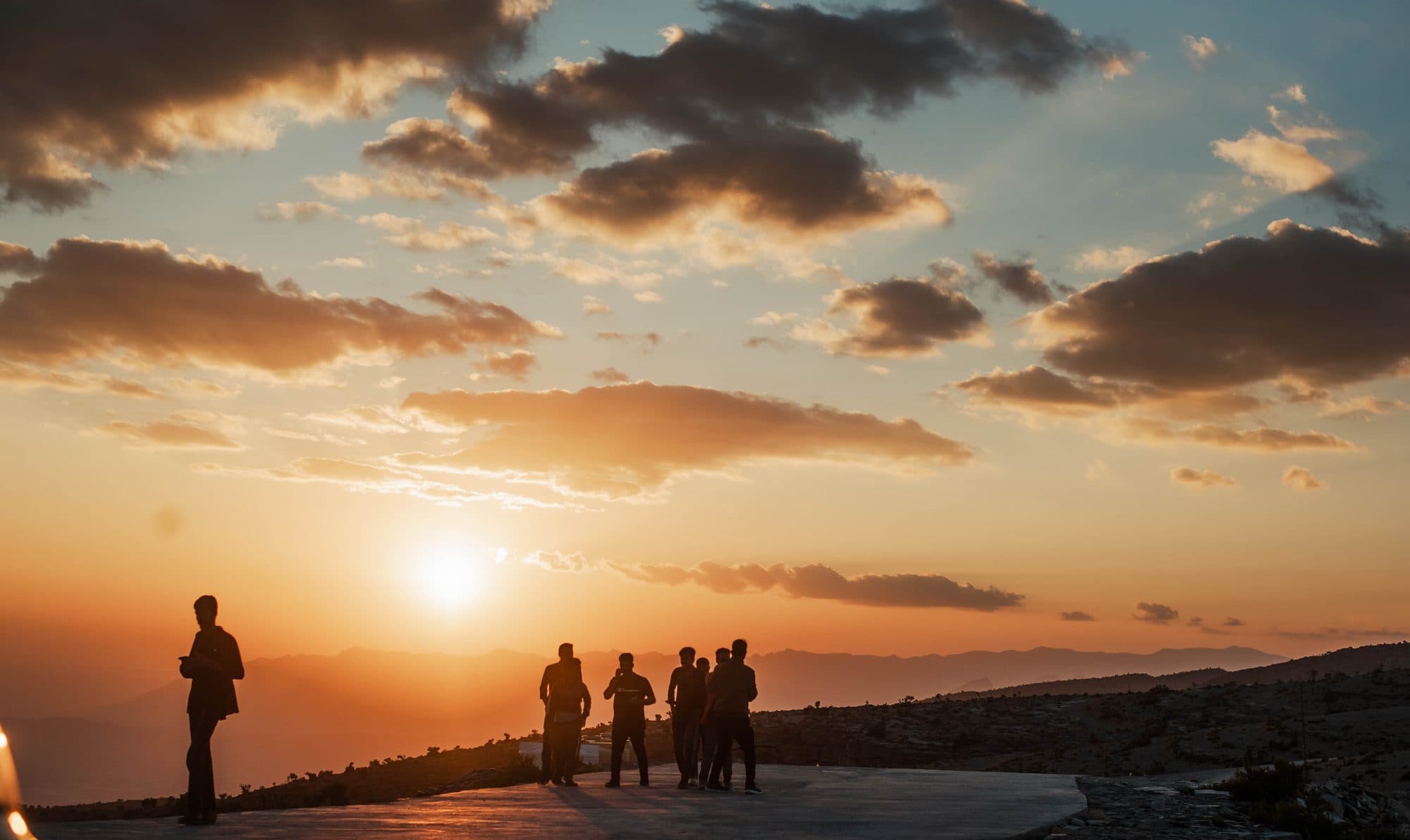 People watching the sunset from a mountain road in Oman